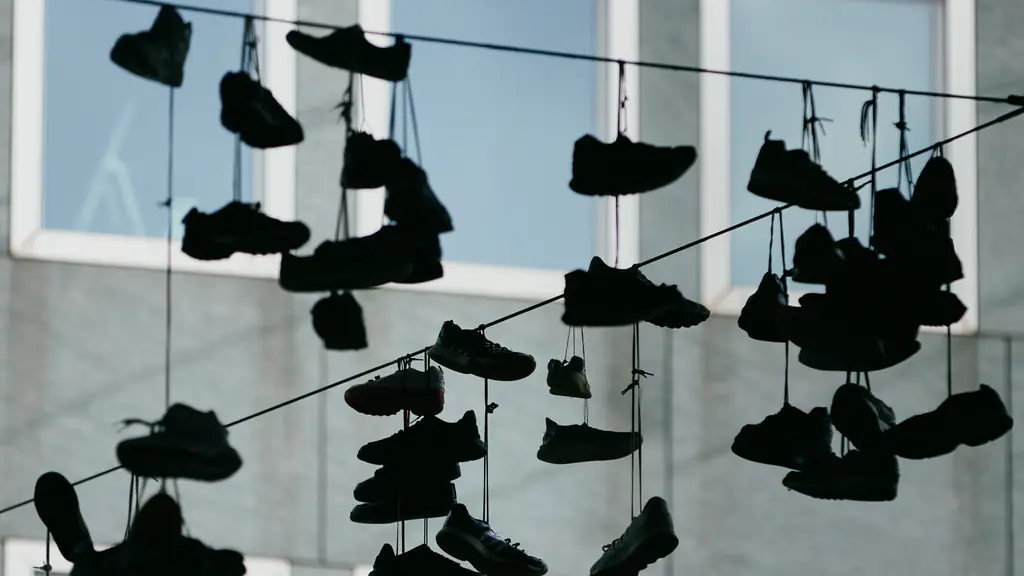 Dozens of sneakers hang by their laces from overhead wires in front of a building's windows